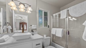 A bathroom with a double sink, toilet, and glass-enclosed shower. - The Wolf House-Best Mountain View’s. (Big Bear Lake)