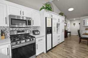 A modern kitchen with white cabinetry, stainless steel appliances, and a herringbone patterned backsplash.