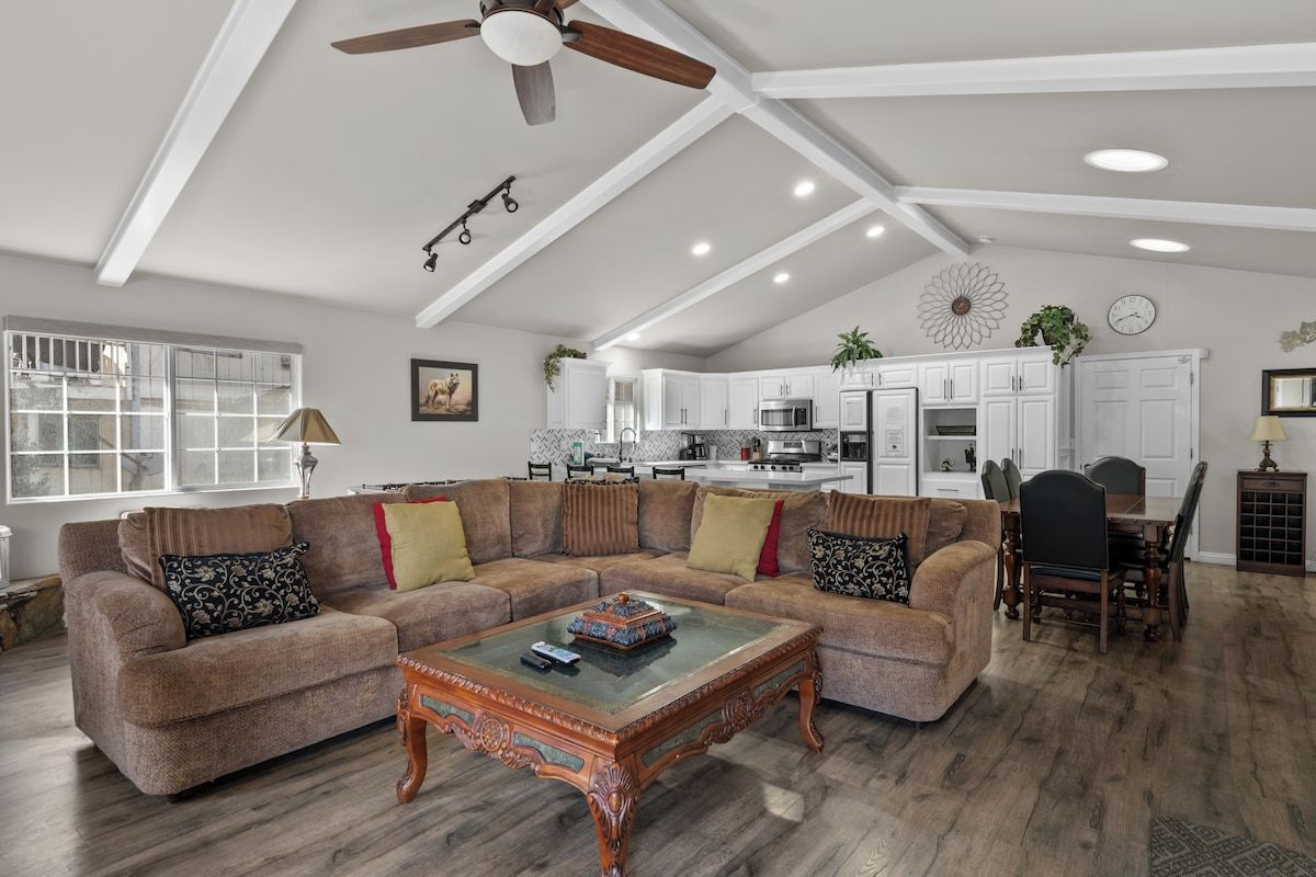 A spacious living room with a sectional sofa, a wooden coffee table, and a ceiling fan.