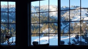 A room with a large window offering a view of a snowy landscape with trees and a clear sky.