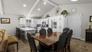 A modern kitchen with white cabinets, a wooden dining table, and a herringbone-patterned backsplash. - The Wolf House-Best Mountain View’s. (Big Bear Lake)
