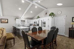 Una cocina moderna con armarios blancos, una mesa de comedor de madera y un salpicadero con diseño tipo espiga.