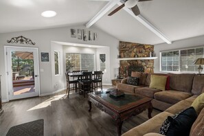 A spacious living room with a fireplace, a dining area with a table and chairs, and a large window. - The Wolf House-Best Mountain View’s. (Big Bear Lake)