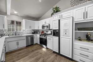 Une cuisine moderne avec des meubles blancs, une cuisinière en acier inoxydable et un réfrigérateur.