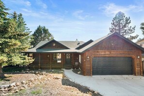 A two-story log cabin with a front porch, a garage, and a driveway.