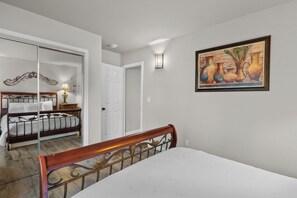 A bedroom with a bed, a nightstand, a lamp, and a painting on the wall.