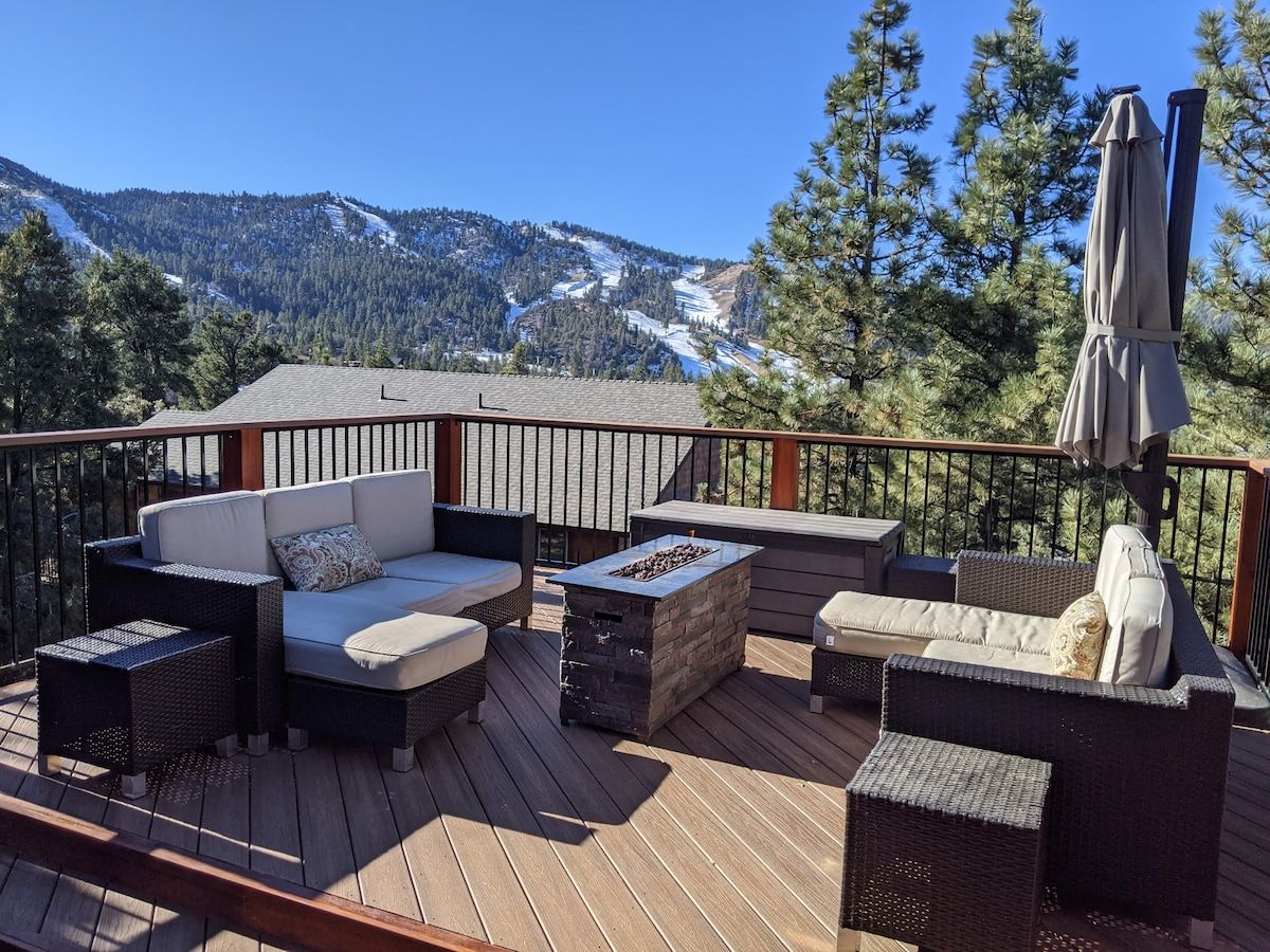 Eine Terrasse mit Gartenmöbeln, einem Feuerkorb und Blick auf die Berge.