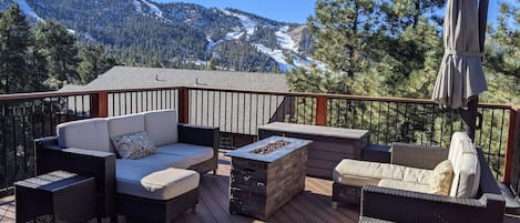 Eine Terrasse mit Gartenmöbeln, einem Feuerkorb und Blick auf die Berge.