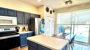 A modern kitchen with dark blue cabinets, stainless steel appliances, and a large island.