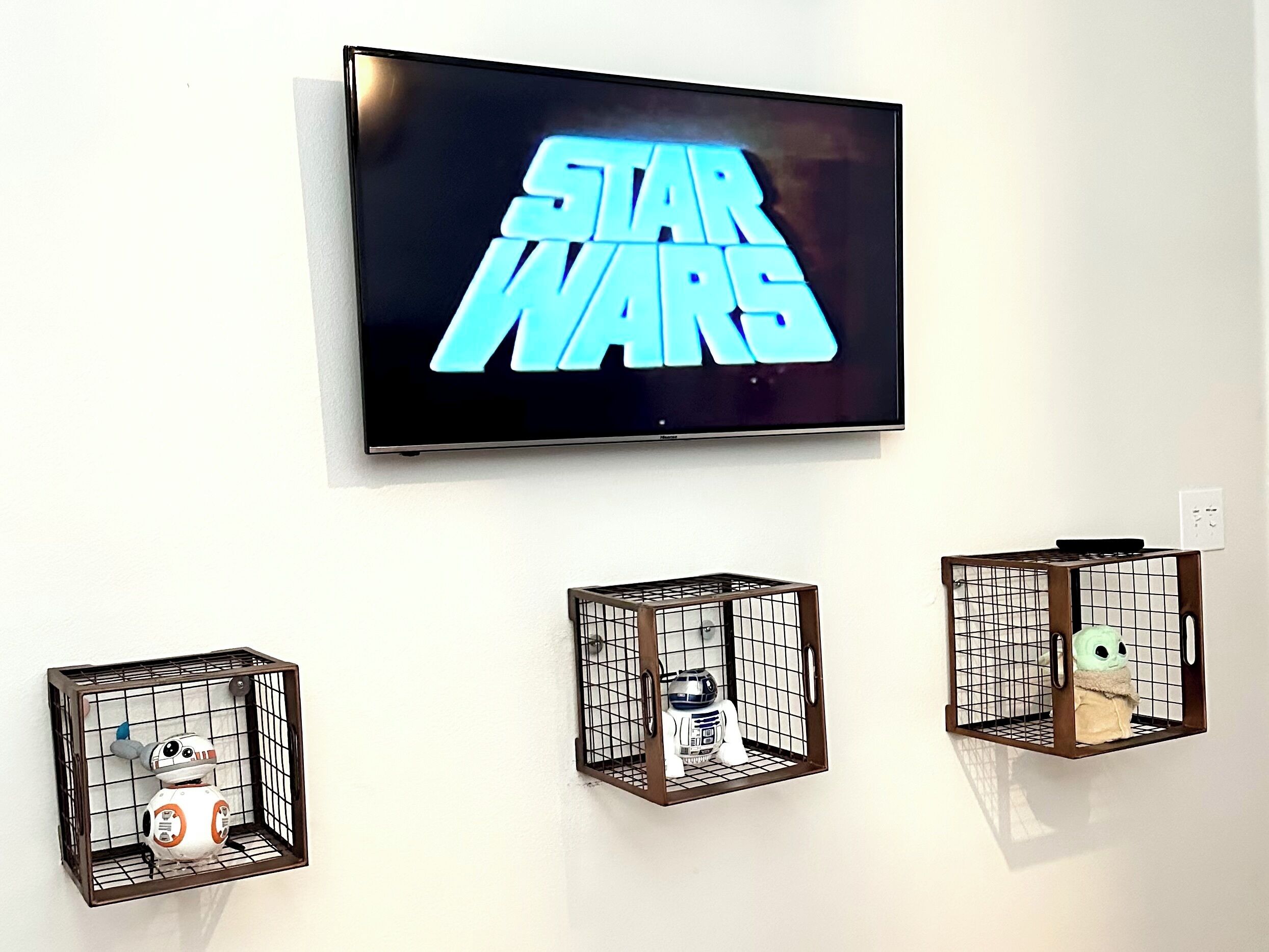 Un téléviseur diffusant des images de «Star Wars » et trois cages suspendues ornées de personnages de «Star Wars ».