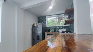 A kitchen with a wooden countertop, a refrigerator, a stove, and a window with a view of trees. - Cabana Multiple premium (San Andrés Islas)