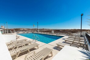A pool area with lounge chairs and a flag.