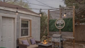 Un pati amb una barbacoa, una xemeneia, un porxo de fusta amb llums i una tanca de set.