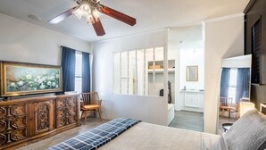 Ein Schlafzimmer mit einem Bett, einer Holzkommode, einem Deckenventilator und einem Bild an der Wand.