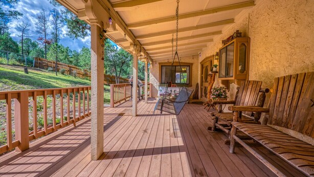 Eine Holzterrasse mit einem Hängestuhl und einem Tisch, einem Holzstuhl und einem Holzschrank.