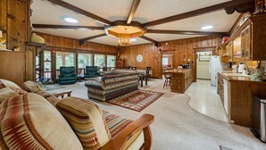 Ein geräumiges Wohnzimmer mit großem Sofa, Essbereich und Küche mit Holzausstattung.