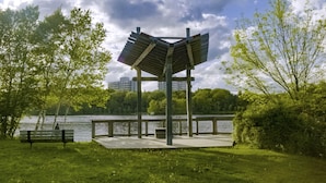 Un parc avec un kiosque en bois, un banc et un lac.