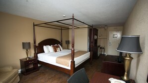 Un lit à baldaquin avec un cadre en bois, une table de chevet avec une lampe, un bureau avec un téléphone et une chaise.