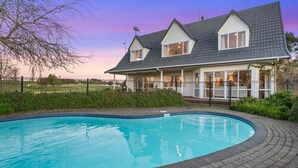 A house with a swimming pool, a fenced yard, and a clear sky. - ⭐The Pond House by Homello⭐ | Pool • Pond • Peaceful Country Retreat (Karaka)