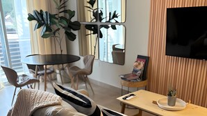 A modern living room with a sofa, a dining table, chairs, and a TV. - URBAN OASIS II (Godoy Cruz)
