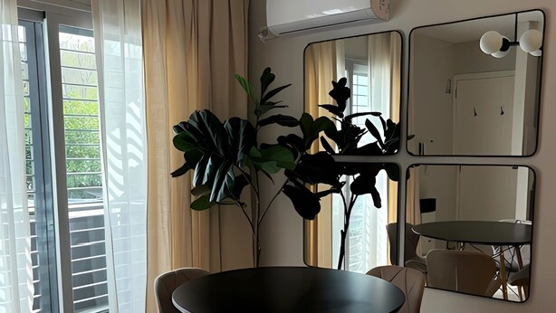 A modern dining area with a round table, four chairs, and a large potted plant. - URBAN OASIS II (Godoy Cruz)