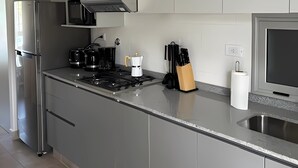 A modern kitchen with stainless steel appliances, a gas stove, and a microwave. - URBAN OASIS II (Godoy Cruz)