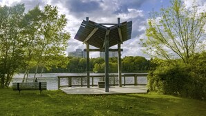A park with a wooden gazebo, a bench, and a lake.