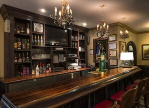 Een bar met houten planken vol flessen, een televisie en een toog met krukken.