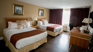 A hotel room with two beds, a desk, and a chair.