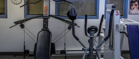 A gym with exercise equipment, a clock, and a poster on the wall.
