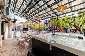 Un jacuzzi con vistas a la ciudad, una parrilla y mobiliario de exterior.