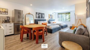 A modern hotel room with a dining area, kitchenette, and a large bed with a view of the outdoors. - Urban Nook MTL – Warm 1BR in the City’s Core (Montréal)