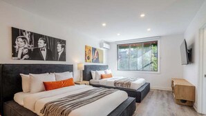 A modern hotel room with two beds, a large window, and artwork on the walls. - Urban Nook MTL – Warm 1BR in the City’s Core (Montréal)