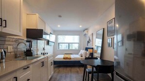 A compact kitchen with a dining area, a built-in bench, and a large window providing natural light. - Hideaway Studio heart DT MTL (Montréal)