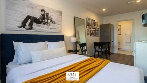 A hotel room with a bed, a desk, a chair, a mirror, and a refrigerator. - Ville-Marie Vibe – Modern Downtown Studio (Montréal)