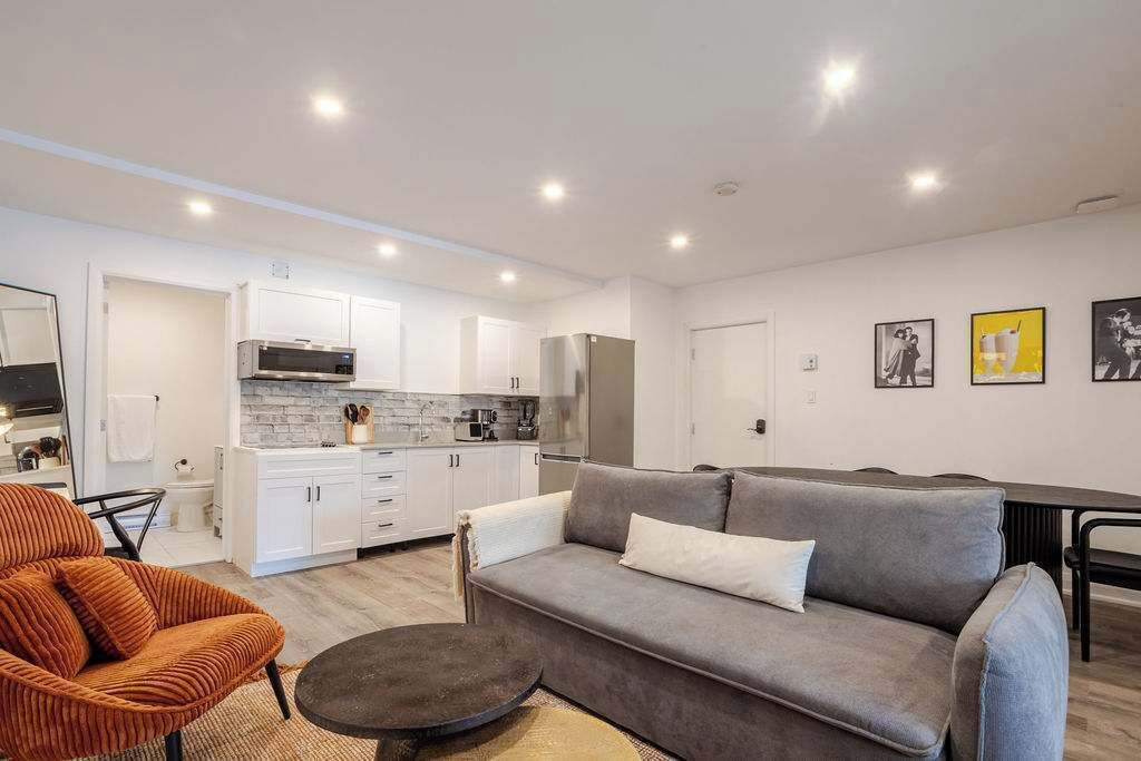 Un salon moderne avec un canapé gris, un fauteuil orange et une table basse ronde.
