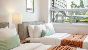 Une chambre d’hôtel avec deux lits, une table de chevet, une lampe et une fenêtre donnant sur l’extérieur.