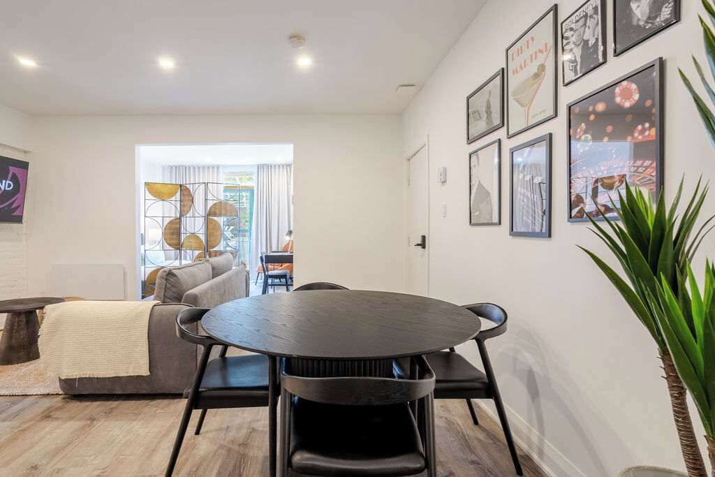Un salon moderne avec une table ronde et des chaises, un canapé gris et une grande plante.