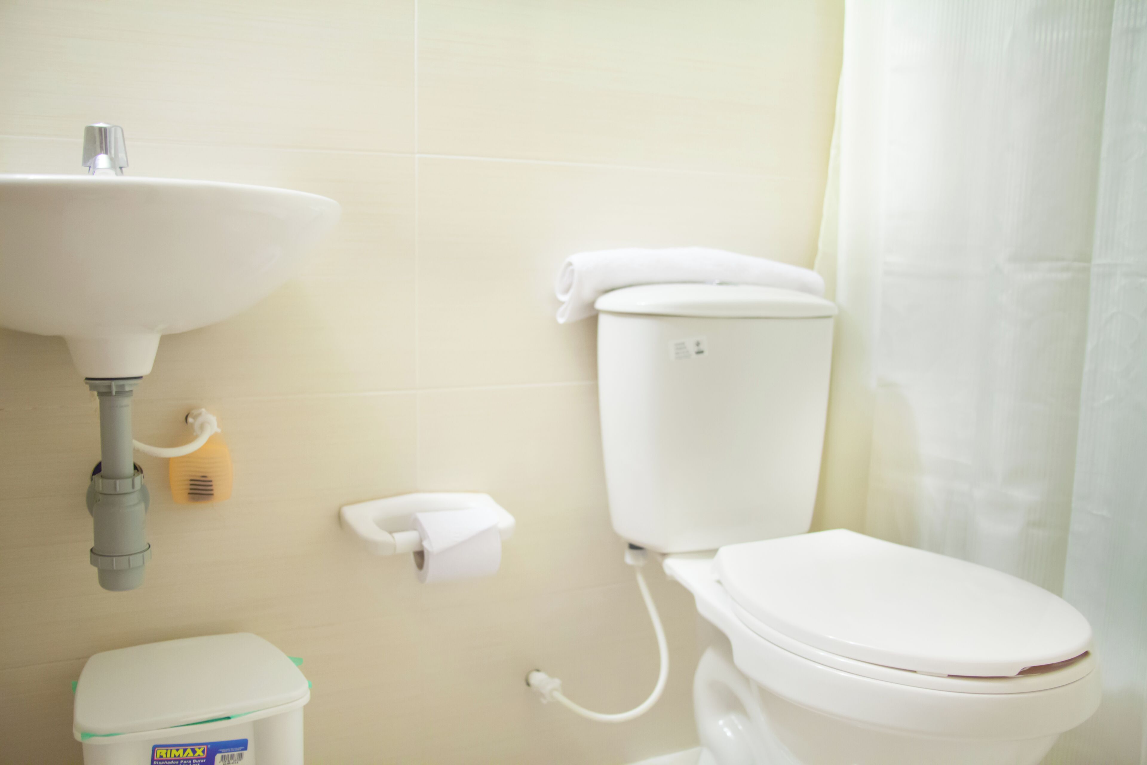 Un baño con un lavamanos blanco, inodoro y un cubo de basura.
