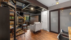 A spacious room with a wooden floor, a white door, and a staircase leading to an upper level. - Rc5b0 (Breckenridge)