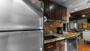 A modern kitchen with stainless steel appliances, granite countertops, and dark wooden cabinets. - Rc5b0 (Breckenridge)