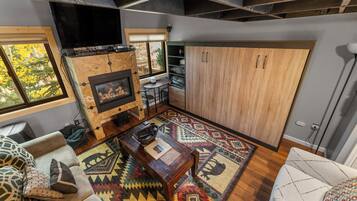 Un salon chaleureux avec une cheminée, des meubles en bois et un tapis à motifs.