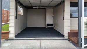 Eine Garage mit dunklem Boden, Holzstufen und einer Tür zu einem überdachten Bereich.