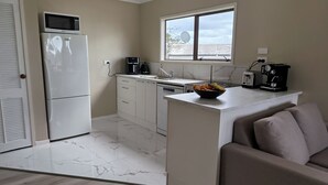 Eine moderne Küche mit Kühlschrank, Mikrowelle, Kaffeemaschine und einer Obstschale auf der Arbeitsfläche.