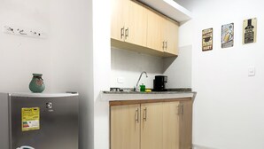 Una cocina compacta con armarios de madera, un lavamanos integrado y un refrigerador.
