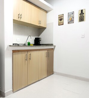 A compact kitchen with wooden cabinets, a built-in sink, and a refrigerator.