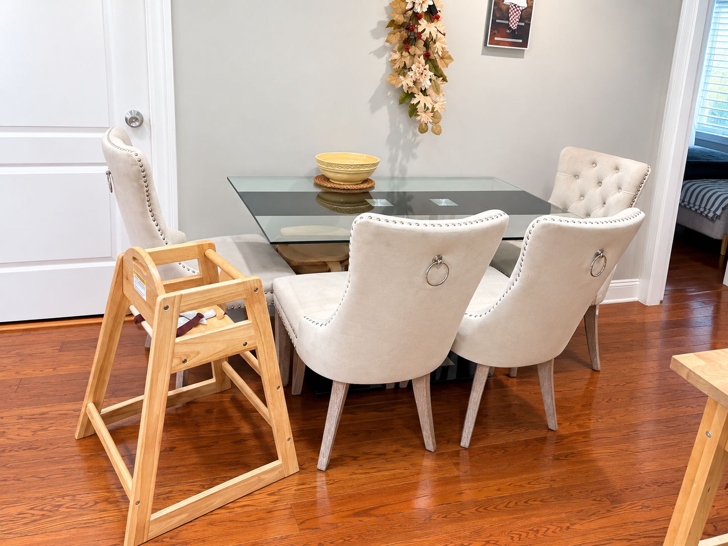 A dining area with a glass table, two upholstered chairs, and a wooden chair.