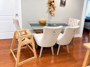 Un coin repas comprenant une table en verre, deux chaises rembourrées et une chaise en bois.