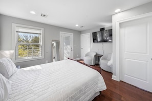 A bedroom with a large bed, a chair, a TV, and a door. - Spacious 3BR 4 Beds Sleeps 8 Near Train Bus 112 Easy NYC Access (Roselle)