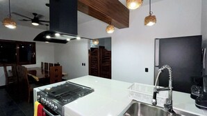 Una cocina moderna con estufa a gas, pileta de acero inoxidable y alacenas de madera.